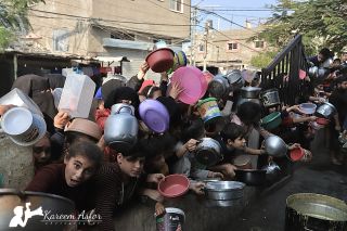 |Palestinians gather from all regions of the south to get their day's food from lentil soup supervised by good people to meet their needs of food.

فلسطينيون يتجمعون من جميع...