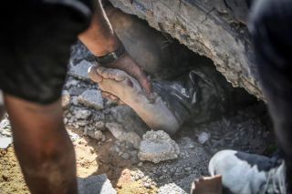 Palestinians try to pull out a body from under the rubble of a destroyed building following Israeli airstrikes on town of Khan Younis, southern Gaza Strip, Thursday, Oct. 26, 2023. Photo Mohammed...