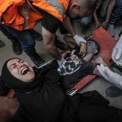 A Palestinian mother mourns near the body of her son lying on a stretcher after it was recovered from the rubble of a destroyed building following an Israeli air strike in Al Nuseirat refugee camp in...