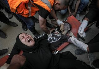 A Palestinian mother mourns near the body of her son lying on a stretcher after it was recovered from the rubble of a destroyed building following an Israeli air strike in Al Nuseirat refugee camp in...
