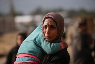 An Internally displaced Palestinian woman carries a child after the Israeli army told residents of #southern Gaza Strip  to leave their homes and head towards west southern #Gaza Strip. 📸 EPA /...