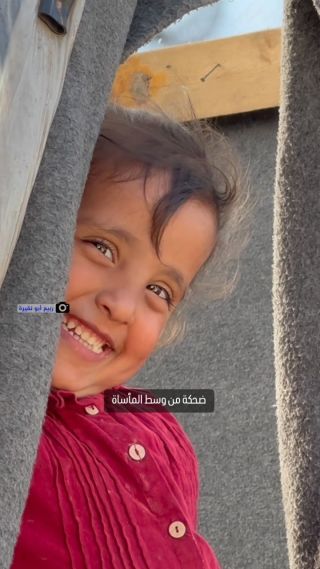 |طفلة فلسطينية تُظهر أسنانها الجميلة ضاحكة، رغم المعاناة والمأساة التي تعيشها مع عائلتها في أحد مخيمات...